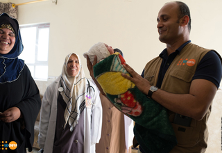 UNFPA Representative in Iraq, Ramanathan Balakrishnan, carrying a new born baby that was delivered during his field visit to Qayyarah delivery room.