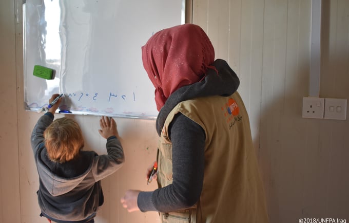 ترغب العديد من النساء في الأطفال، ويواجهن خيبة أمل أو حتى وصمة عار إن لم يكن باستطاعتهن ذلك. صورة مستشارة تعمل في احدى المراكز المدعومة من صندوق الأمم المتحدة للسكان في العراق تعلم طفلاً لاجئاً.  ©صورة صندوق الأمم المتحدة للسكان في العراق