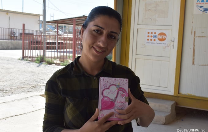 Sana’ holding her notebook where she writes down her most cherished memories since she arrived to Iraq.  © UNFPA Iraq/Salwa Moussa