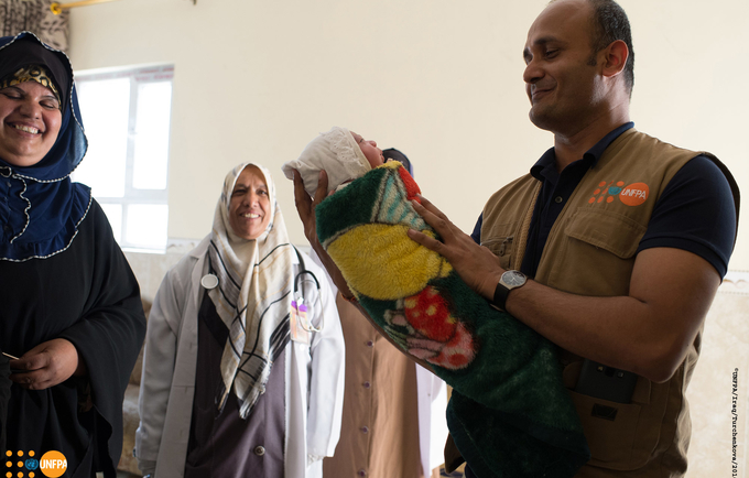 UNFPA Representative in Iraq, Ramanathan Balakrishnan, carrying a new born baby that was delivered during his field visit to Qayyarah delivery room.